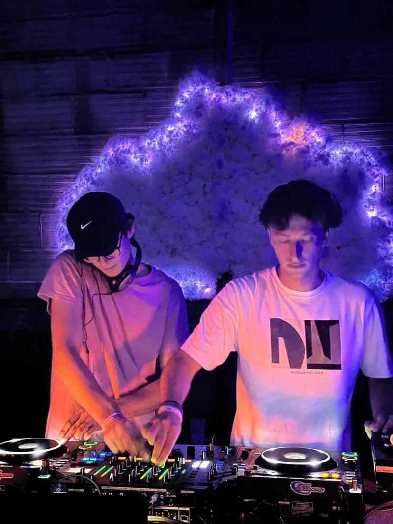Deux DJ de Baska Events aux platines devant un décor lumineux, pendant un festival